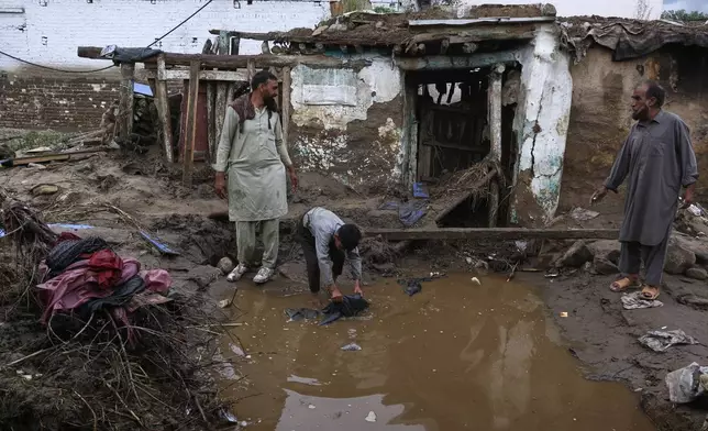 Villagers collect usable items through the rubble of their partially damaged home following Friday's flash flooding at a neighbourhood of Pir Baba, an area of Buner district, in Pakistan's northwest, Sunday, Aug. 17, 2025. (AP Photo/Muhammad Sajjad)