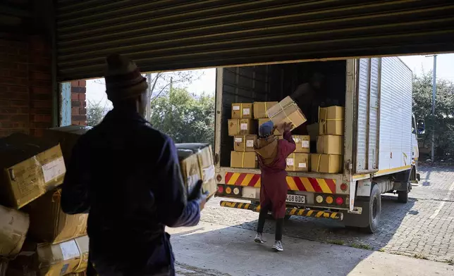 Workers load a truck with the last boxes filled with clothes from the empty Tzicc clothing factory following the threat of U.S.-imposed tariffs in Maseru, Lesotho, Tuesday, July 22, 2025. (AP Photo/Bram Janssen)