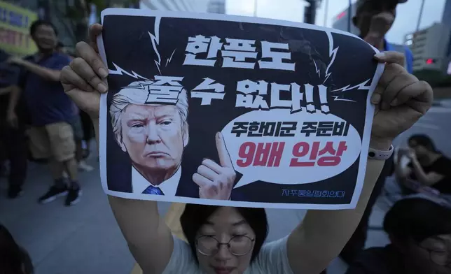 A South Korean protester holds up a banner during a rally against U.S. President Donald Trump's tariffs policy on South Korea, near the U.S. Embassy in Seoul, South Korea, Wednesday, July 30, 2025. The signs at bottom read "We can't give you a penny." (AP Photo/Ahn Young-joon)