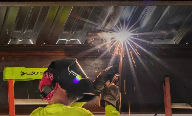 A welder works on steel decking during construction of a housing project, Thursday, July 31, 2025, in Portland, Maine. (AP Photo/Robert F. Bukaty)