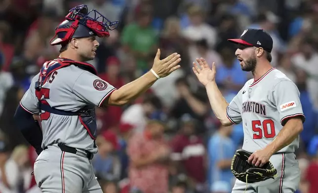 Washington Nationals' PJ Poulin, right, and Riley Adams celebrate after the Nationals won a baseball game against the Philadelphia Phillies Friday, Aug. 22, 2025, in Philadelphia. (AP Photo/Matt Slocum)