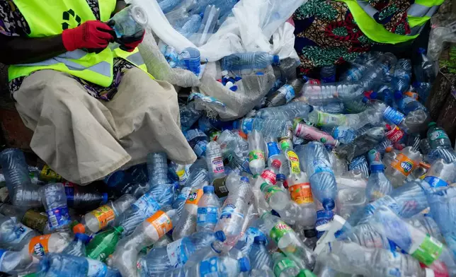 Workers use razor blades to scrape off labels from different soft-drink plastic bottles at the Street Waste Company in Lagos, Nigeria, Monday, Aug 11, 2025. (AP Photo/Sunday Alamba)