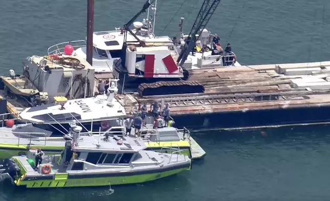 This image taken from video provided by WSVN-TV shows Miami-Dade Fire Rescue and others in boats around what appears to be a barge involved in an accident with a group of kids and an adult on a sailing boat during a sailing camp, Monday, July 28, 2025, in Miami. (WSVN-TV via AP)