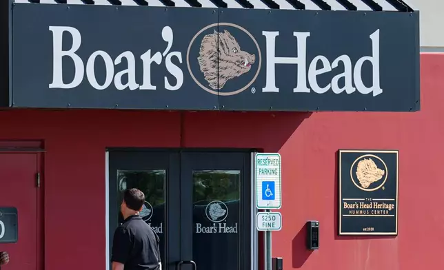 Workers gather outside the entrance of a Boar's Head deli meat plant in New Castle, Ind., Wednesday, Aug. 6, 2025. (AP Photo/Michael Conroy)