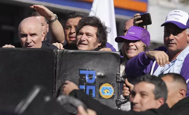 Police shield Argentine President Javier Milei and his sister, Secretary General of the Presidency, Karina Milei, from objects thrown at them by protesters amid a campaign rally ahead of legislative provincial elections in Lomas de Zamora, Argentina, Wednesday, Aug. 27, 2025. (AP Photo/Natacha Pisarenko)