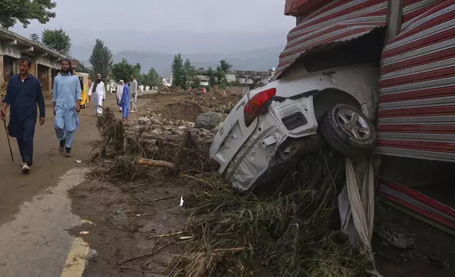 Local residents walk past shops damaged after Friday's flash flooding on the outskirts of Pir Baba, Buner district, in Pakistan's northwest, Saturday, Aug. 16, 2025. (AP Photo/Muhammad Sajjad)