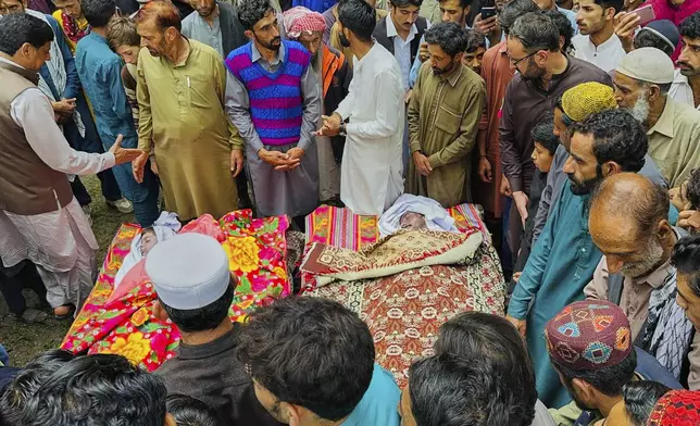 People gather around the bodies of the victims of a cloudburst incident, sudden intense downpours, after funeral prayers, in Naryan Behak village near Muzaffarabad, the main town of Pakistan's controlled Kashmir, Friday, Aug. 15, 2025. (AP Photo/M.D. Mughal)