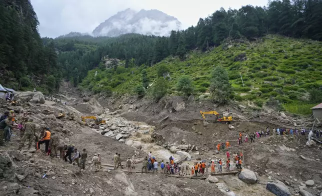 Stranded pilgrims are helped across a water channel using a makeshift bridge a day after flash floods in Chositi village, Kishtwar district, Indian-controlled Kashmir, Friday, Aug. 15, 2025. (AP Photo/Channi Anand)