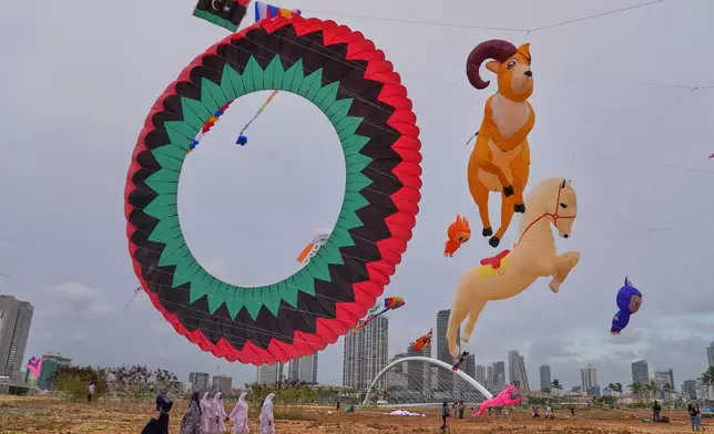 Sri Lankan girls walk past kites of different shapes and sizes at the Colombo International Kite Festival in Colombo, Sri Lanka, Saturday, Aug. 23, 2025. (AP Photo/Eranga Jayawardena)