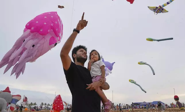A man and his daughter attend the Colombo International Kite Festival in Colombo, Sri Lanka, Saturday, Aug. 23, 2025. (AP Photo/Eranga Jayawardena)