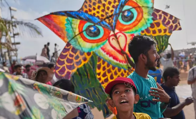 A boy watches participants fly kite during the Colombo International Kite Festival in Colombo, Sri Lanka, Sunday, Aug. 24, 2025. (AP Photo/Eranga Jayawardena)