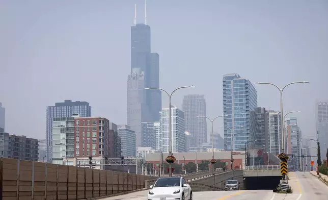 People drive on South Clark Street near West 15th Street on the South Side as a haze of Canadian wildfire smoke blankets the Chicago area and creates poor air quality, Thursday, July 31, 2025. (Ashlee Rezin/Chicago Sun-Times via AP)
