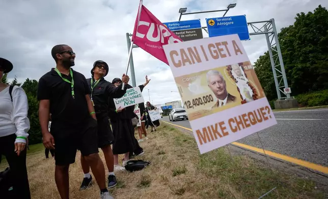 A sign with a photo of Air Canada CEO Michael Rousseau on it is seen as striking Air Canada flight attendants rally at Vancouver International Airport, in Richmond, British Columbia, Monday, Aug. 18, 2025. (/Darryl Dyck/The Canadian Press via AP)