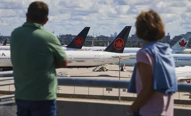 Travelers look out over grounded Air Canada planes as flight attendants picket at Pearson International Airport in Toronto, Monday, Aug. 18, 2025. (Sammy Kogan/The Canadian Press via AP)