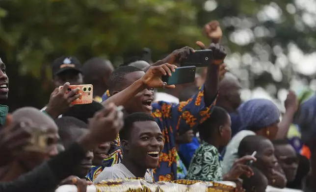 Onlookers film on mobile phones as people dressed in costumes perform during the mask festival in Porto-Novo, Benin , Sunday, Aug. 3, 2025. (AP Photo/Sunday Alamba)