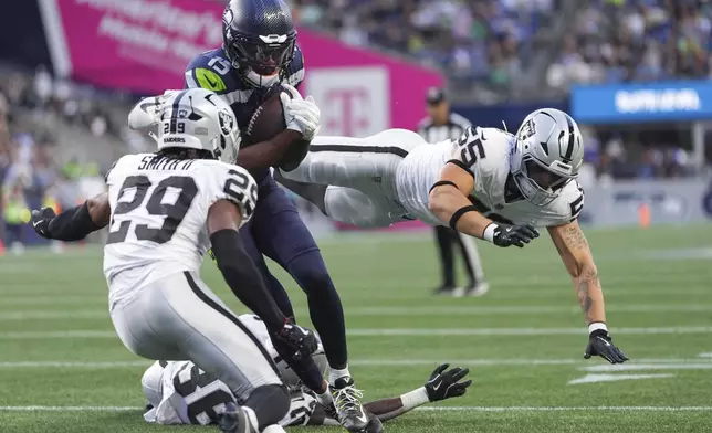Seattle Seahawks wide receiver Tory Horton (15) goes to score against Las Vegas Raiders safety Chris Smith II (29) and linebacker Cody Lindenberg (55) during the first half of an NFL preseason football game Thursday, Aug. 7, 2025, in Seattle. (AP Photo/Lindsey Wasson)
