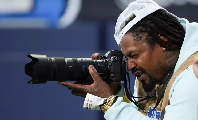 Former NFL player Marshawn Lynch takes photos during an NFL preseason football game between the Seattle Seahawks and the Las Vegas Raiders, Thursday, Aug. 7, 2025, in Seattle. (AP Photo/Lindsey Wasson)