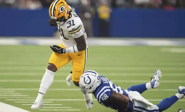 Green Bay Packers running back Emanuel Wilson (31) is tackled by Indianapolis Colts linebacker Austin Ajiake (58) during the first half of a preseason NFL football game, Saturday, Aug. 16, 2025, in Indianapolis. (AP Photo/Michael Conroy)