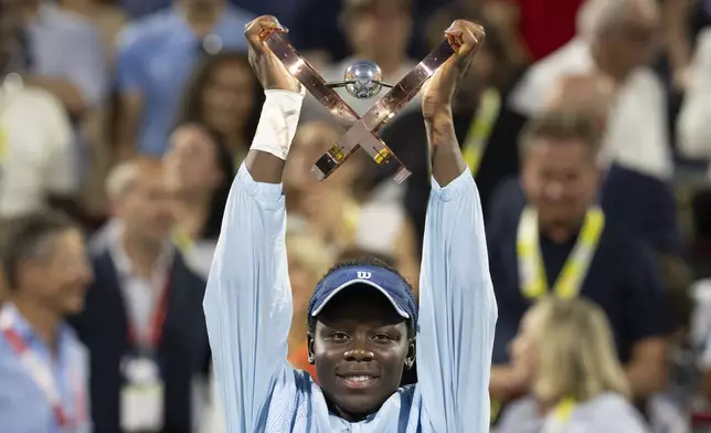 Victoria Mboko, of Canada, hoists the trophy following her win over Naomi Osaka, of Japan, in final action at the National Bank Open women's tennis tournament in Montreal, Thursday, Aug. 7, 2025. (Christinne Muschi/The Canadian Press via AP)