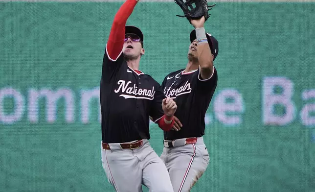 Washington Nationals center fielder Robert Hassell III, left, beats Daylen Lile to catch a one-run sacrifice fly hit by Kansas City Royals' Bobby Witt Jr. during the eighth inning of a baseball game Wednesday, Aug. 13, 2025, in Kansas City, Mo. (AP Photo/Charlie Riedel)