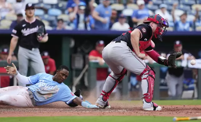 Kansas City Royals' Tyler Tolbert (2) beats the tag by Washington Nationals catcher Riley Adams to score the game-tying run on a sacrifice fly hit by Bobby Witt Jr. during the eighth inning of a baseball game Wednesday, Aug. 13, 2025, in Kansas City, Mo. (AP Photo/Charlie Riedel)