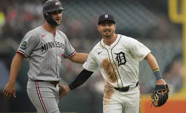 Detroit Tigers shortstop Zach McKinstry, right, and Minnesota Twins' Matt Wallner react while walking off the field during the fourth inning of a baseball game, Monday, Aug. 4, 2025, in Detroit. (AP Photo/Ryan Sun)