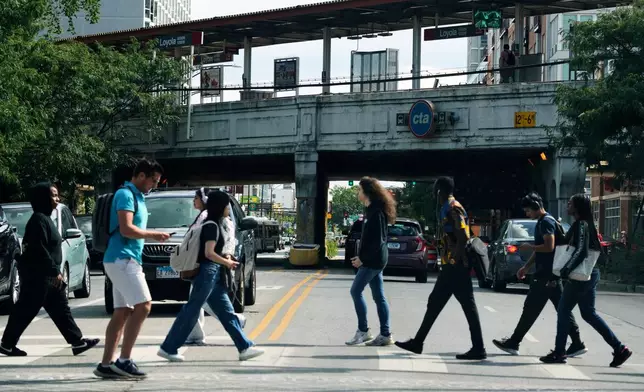 Pedestrians cross a street in front of a CTA station in Chicago, Tuesday, Aug. 26, 2025. (AP Photo/Nam Y. Huh)