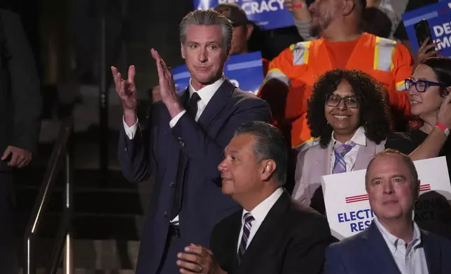 California Gov. Gavin Newsom, left, applauds as he stands above Sen. Adam Schiff, D-Calif., below right, and Sen. Alex Padilla, D-Calif., below center, during a news conference Thursday, Aug. 14, 2025, in Los Angeles. (AP Photo/Marcio Jose Sanchez)