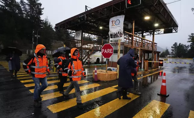 Workers walk at the entrance of El Teniente copper mine, operated by Codelco in Chile, where a collapse killed one worker and trapped five others underground, leading to a suspension of operations in Rancagua Chile, Friday, Aug. 1, 2025. (AP Photo/Esteban Felix)