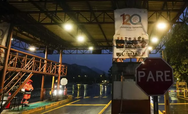 A worker stands at the entrance of El Teniente copper mine, operated by Codelco, where a collapse killed one worker and trapped five others underground, leading to a suspension of operations in Rancagua Chile, Friday, Aug. 1, 2025. (AP Photo/Esteban Felix)