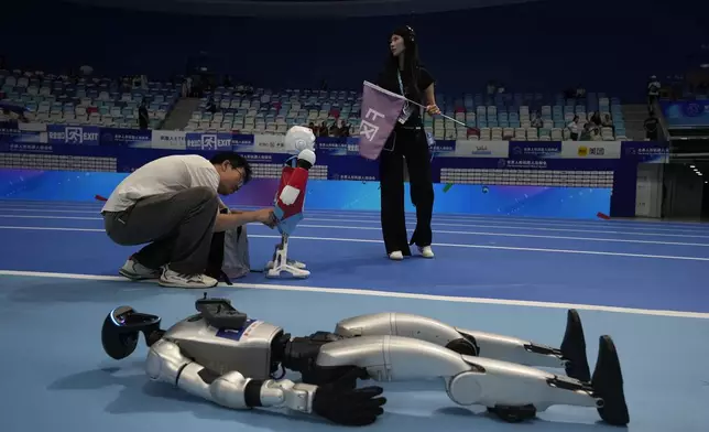A worker prepares a robot before the opening ceremony of The World Humanoid Robot Games held in Beijing, China, Thursday, Aug. 14, 2025. (AP Photo/Ng Han Guan)