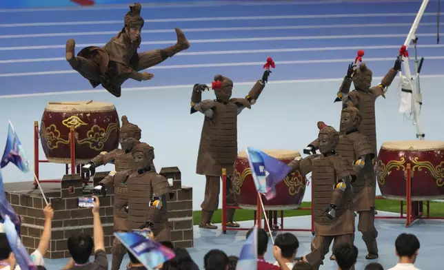 A human performer leaps above robots dressed like terracotta warriors during the opening ceremony of The World Humanoid Robot Games held in Beijing, China, Thursday, Aug. 14, 2025. (AP Photo/Ng Han Guan)