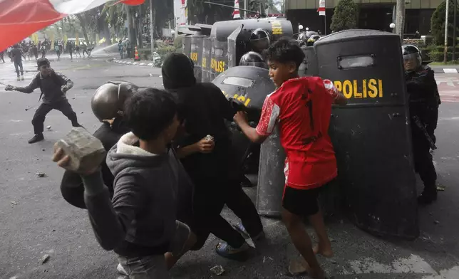 People throw rocks at the police during a protest following the death of a delivery rider in clashes between riot police and students protesting against lawmakers' allowances, in Medan, North Sumatra, Indonesia, Friday, Aug. 29, 2025. (AP Photo/Binsar Bakkara)