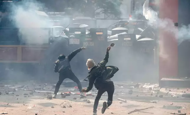 Protesters clash with riot police officers following the death of a delivery rider in clashes between riot police and students protesting against lawmakers' allowances, in Jakarta, Indonesia, Friday, Aug. 29, 2025. (AP Photo/Achmad Ibrahim)