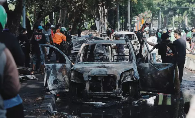 People inspect the wreckage of cars burned in Thursday's rally against lavish allowances given to parliament members, in Jakarta, Indonesia, Friday, Aug. 29, 2025. (AP Photo/Achmad Ibrahim)