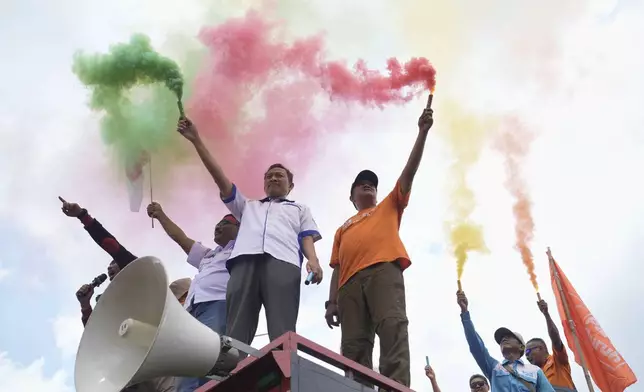 Indonesian laborers light flares during a rally against outsourcing and low wages outside the parliament in Jakarta, Indonesia, Thursday, Aug. 28, 2025. (AP Photo/Tatan Syuflana)