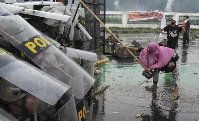 A protester attacks riot police with a bamboo pole during a protest against lavish allowances given to parliament members, in Jakarta, Indonesia, Thursday, Aug. 28, 2025. (AP Photo/Tatan Syuflana)