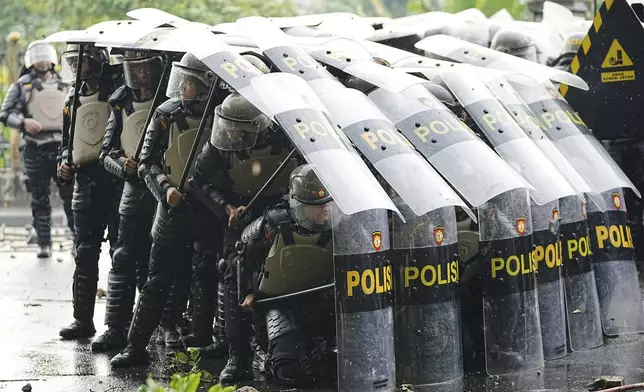 Riot police officers take defensive position as they clash with protesters during a protest against lavish allowances given to parliament members, in Jakarta, Indonesia, Thursday, Aug. 28, 2025. (AP Photo/Achmad Ibrahim)