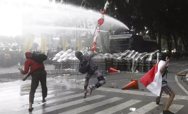 People throw rocks at the police during a protest following the death of a delivery rider in clashes between riot police and students protesting against lawmakers' allowances, in Medan, North Sumatra, Indonesia, Friday, Aug. 29, 2025. (AP Photo/Binsar Bakkara)