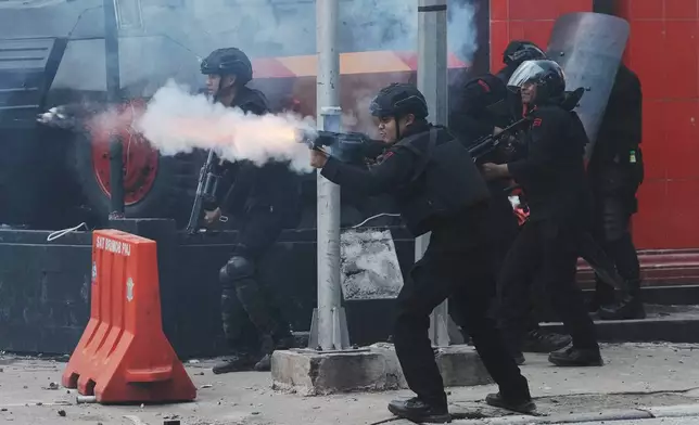 Police officers fire tear gas at protesters following the death of a delivery rider in clashes between riot police and students protesting against lawmakers' allowances, in Jakarta, Indonesia, Friday, Aug. 29, 2025. (AP Photo/Achmad Ibrahim)