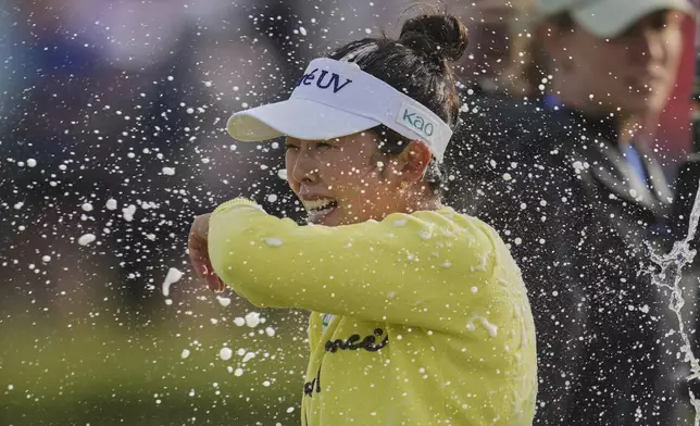 Miyu Yamashita of Japan is sprayed with champagne as she celebrates after winning the Women's British Open golf championship, at Royal Porthcawl Golf Club in Porthcawl, Wales, Sunday, Aug. 3, 2025. (AP Photo/Kin Cheung)