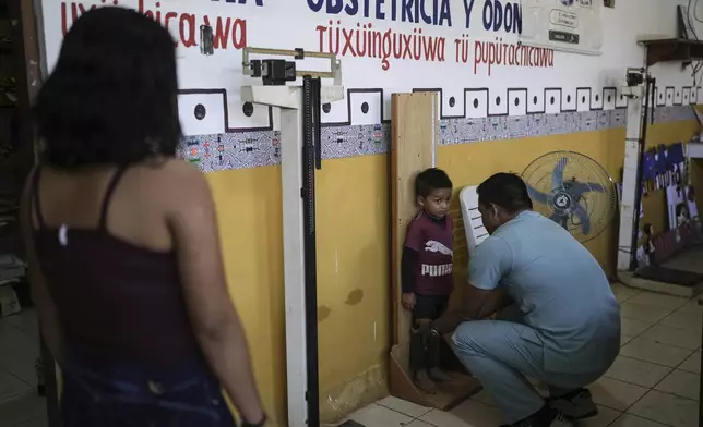 A doctor measures a child's height at the health center in Santa Rosa, Peru, an island on the Amazon River at the triple border with Colombia and Brazil, Monday, Aug. 18, 2025.(AP Photo/Ivan Valencia)