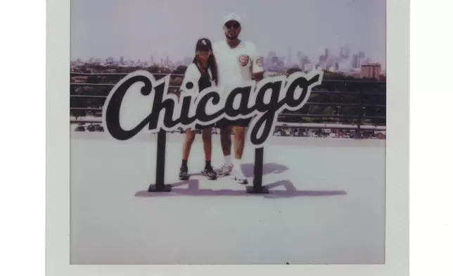 Aylin Servin, 8, left, and her father Aldo Servin have their photo taken with the "Chicago" sign during a Chicago Cubs versus Chicago White Sox Crosstown Classic series baseball game Sunday, July 27, 2025, in Chicago. (AP Photo/Erin Hooley)