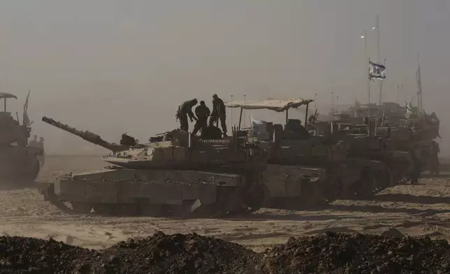 Israeli soldiers stand on the top of a tank parked on an area near the Israeli-Gaza border, as seen from southern Israel, Monday, Aug. 18, 2025. (AP Photo/Maya Levin)