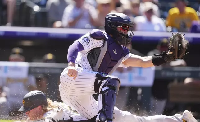 Colorado Rockies catcher Hunter Goodman, front, fields the throw as Pittsburgh Pirates' Jack Suwinski scores on a ground out hit by Spencer Horwitz in the eighth inning of a baseball game Sunday, Aug. 3, 2025, in Denver. (AP Photo/David Zalubowski)