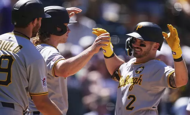 Pittsburgh Pirates' Spencer Horwitz, right, is congratulated as he crosses home plate after hitting a three-run home run by Jared Triolo, left, and Jack Suwinski in the sixth inning of a baseball game against the Colorado Rockies, Sunday, Aug. 3, 2025, in Denver. (AP Photo/David Zalubowski)
