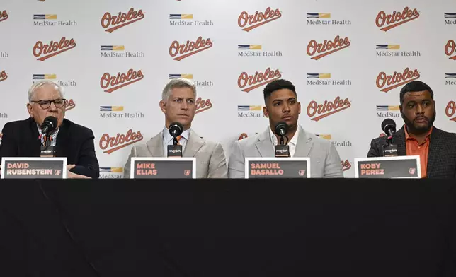 From left to right, Baltimore Orioles owner David Rubenstein, executive vice president and general manager Mike Elias, rookie catcher Samuel Basallo and vice president of international scouting Koby Perez take questions from the media during Basallo's contract extension press conference Saturday, Aug. 23, 2025, in Baltimore. (AP Photo/Terrance Williams)