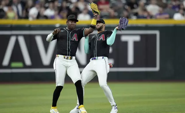 Arizona Diamondbacks shortstop Geraldo Perdomo, left, makes a catch on a pop fly hit by Cleveland Guardians' Daniel Schneemann as Perdomo avoids colliding with Diamondbacks left fielder Lourdes Gurriel Jr., right, during the first inning of a baseball game Monday, Aug. 18, 2025, in Phoenix. (AP Photo/Ross D. Franklin)