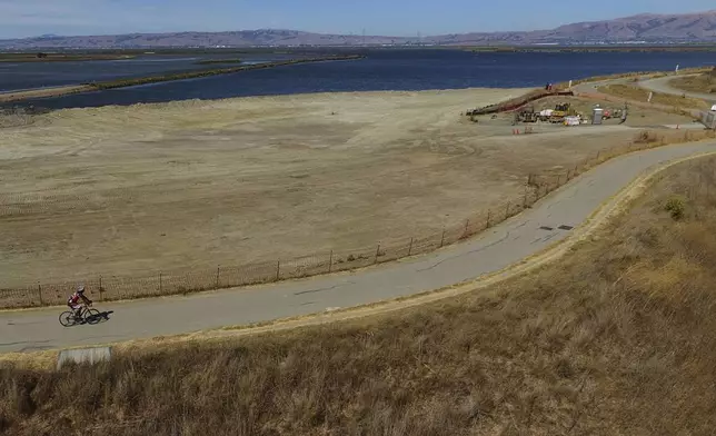A cyclist travels on a trail along the the Pond A1 site for the South Bay Salt Pond Restoration Project, Thursday, Aug. 7, 2025, in Mountain View, Calif. (AP Photo/Godofredo A. Vásquez)