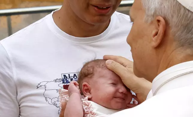 Pope Leo XIV caresses a baby as he arrives to celebrate a Mass at the Sanctuary of Santa Maria della Rotonda in Albano Laziale, near Rome, Sunday, Aug. 17, 2025. (AP Photo/Riccardo De Luca)